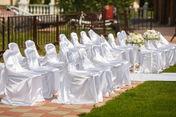 Καρέκλες ντυμένες στο Λευκό Σατέν περιμένει τους επισκέπτες του γάμου — Φωτογραφία Αρχείου