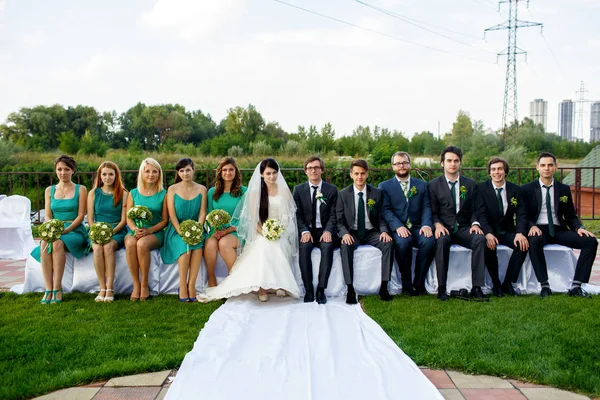 Recém-casados e seus amigos sentam-se ao ar livre no branco — Fotografia de Stock