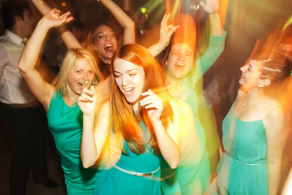 Girls in mint dresses have fun dancing in yellow lights — Stock Photo, Image