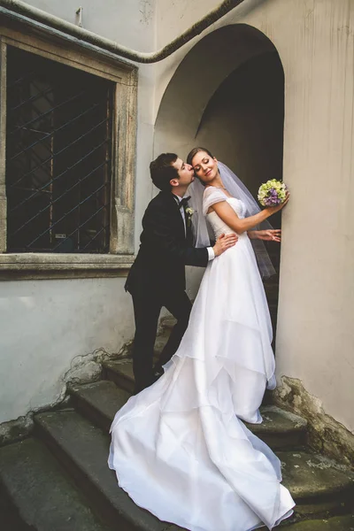 Noivo beija bochecha da noiva dobrando-a na entrada — Fotografia de Stock