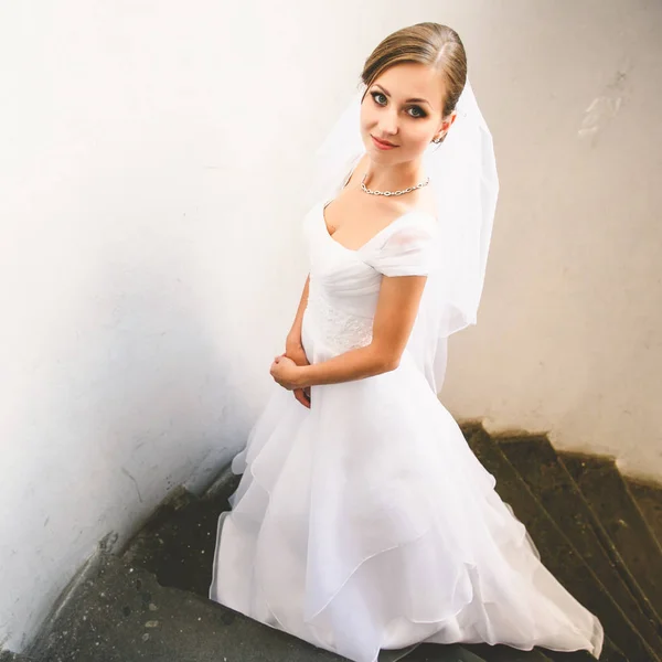 Bruid kijkt verlegen poseren op de stenen trap — Stockfoto
