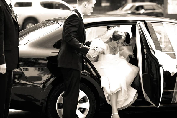 Groomsman aide la mariée à sortir de la voiture — Photo