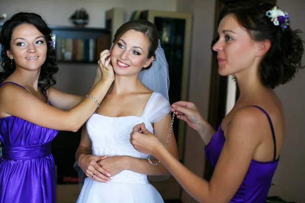 Las damas de honor ayudan a la novia a ponerse pendientes y collar — Foto de Stock