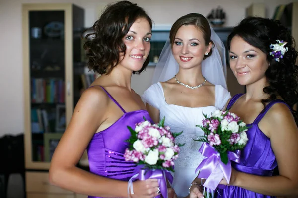 Les demoiselles d'honneur tiennent des bouquets violets pendant qu'elles posent avec une mariée — Photo