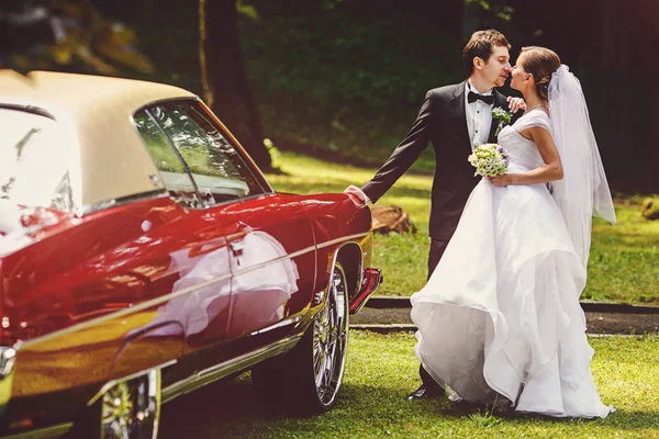 Sposi bacio dietro una vecchia auto americana — Foto Stock