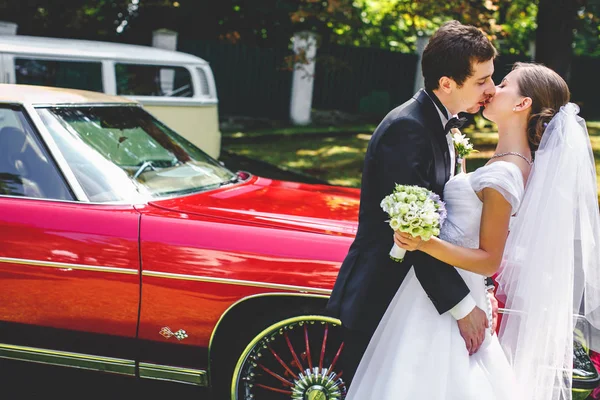 Um beijo apaixonado de recém-casados atrás do velho Dodge vermelho — Fotografia de Stock