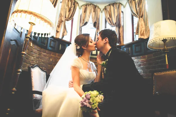 Noiva e noivo beijam sentado em um salão vintage — Fotografia de Stock