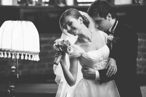 Groom devaneios segurando uma noiva bonita com um buquê em seu braço — Fotografia de Stock