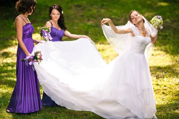 Noiva se sente como um pássaro de pé com damas de honra no parque — Fotografia de Stock