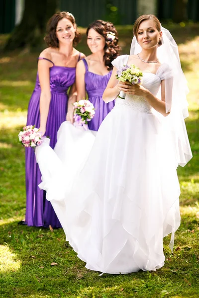 Novia sostiene un ramo de boda en sus manos mientras las damas de honor coche —  Fotos de Stock