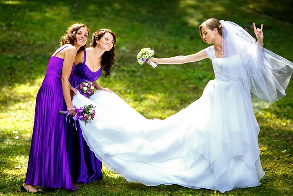 Bride rock's the world posing with bridesmaids in the park — Stock Photo, Image