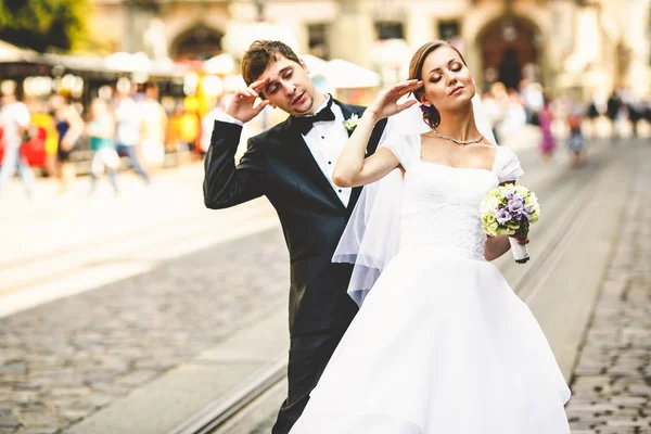 Los recién casados juegan cansados de pie en la calle en un día soleado — Foto de Stock