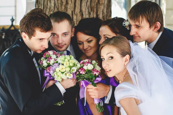 Braut und Bräutigam posieren mit Freunden, die Hochzeitssträuße riechen — Stockfoto