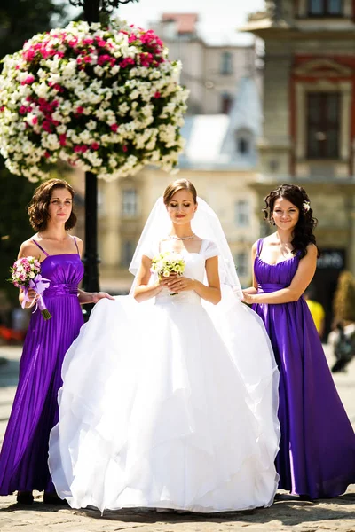 Demoiselles d'honneur en robes violettes entourent une mariée dans la rue — Photo