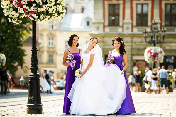 Las damas de honor levantan una falda del vestido de novia mientras posan juntos —  Fotos de Stock