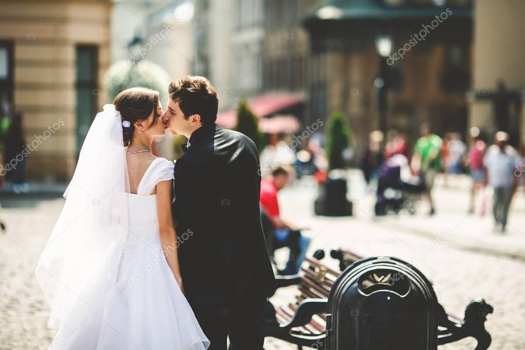 Bride and groom kiss while walking along streets of old Lviv