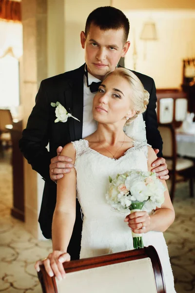 Braut und Bräutigam schauen nachdenklich, während er sie von hinten umarmt — Stockfoto