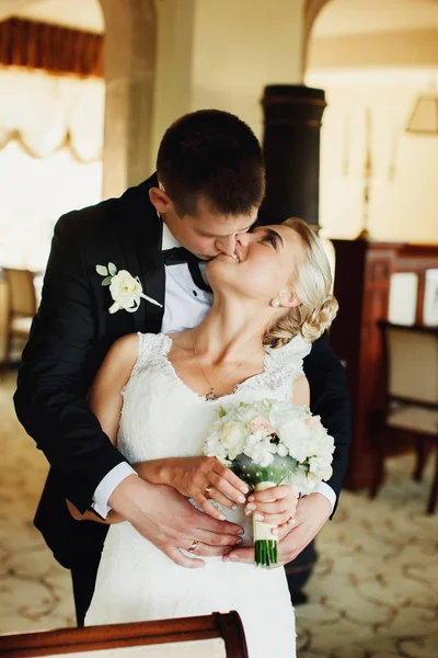 Groom beija uma noiva sorridente abraçando-a por trás — Fotografia de Stock