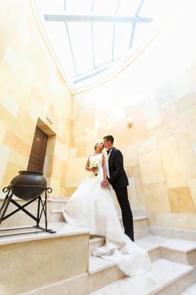 新郎和新娘接吻，站在玻璃下的白色楼梯细胞 — 图库照片