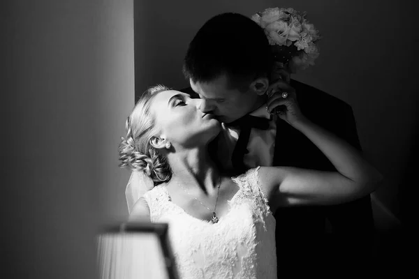 Mariée atteint le visage du marié dans un baiser tandis que le soleil éclaire th — Photo