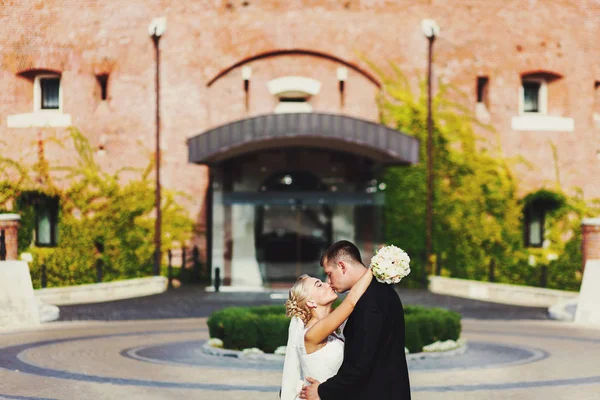 Ein Hochzeitspaar küsst sich vor einem Eingang zu einem alten Haus — Stockfoto