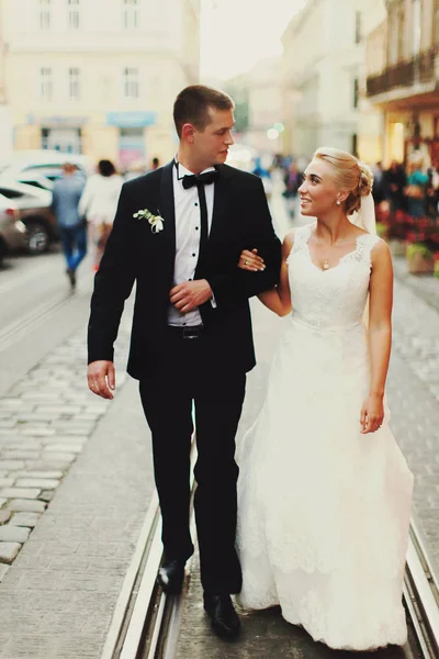 Felices recién casados caminan a lo largo de los tranvías en la ciudad vieja — Foto de Stock