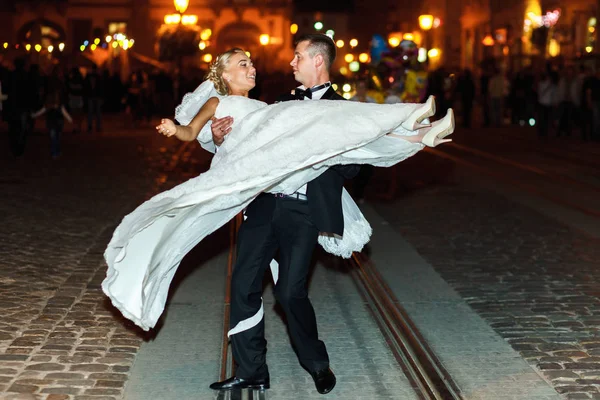 Groom gira uma noiva em algum lugar na cidade velha à noite — Fotografia de Stock
