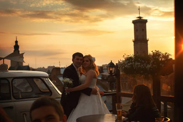 Braut und Bräutigam posieren im Abendlicht des Cafés auf dem Ro — Stockfoto