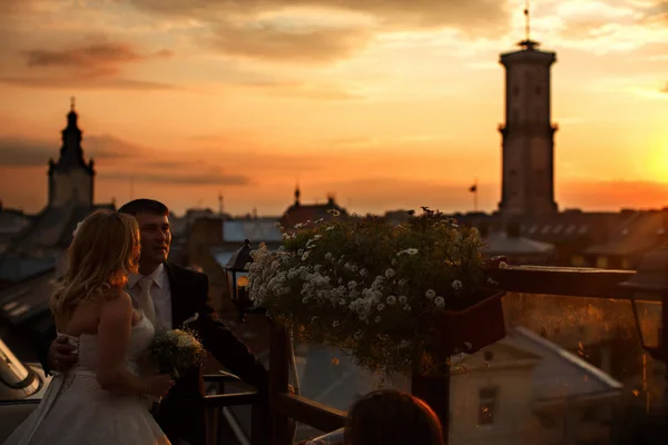 Γαμπρός κατέχει στη μέση της νύφης που στέκεται στην οροφή και wathcing ένα su — Φωτογραφία Αρχείου