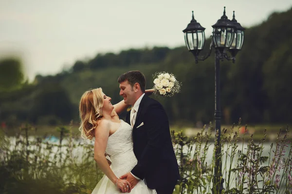 Наречена і наречена обіймаються стоячи перед старим ліхтарем — стокове фото