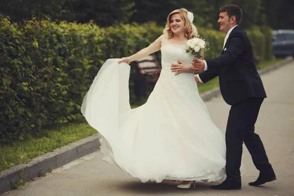 Bruid wervelingen terwijl de bruidegom probeert te vangen haar — Stockfoto