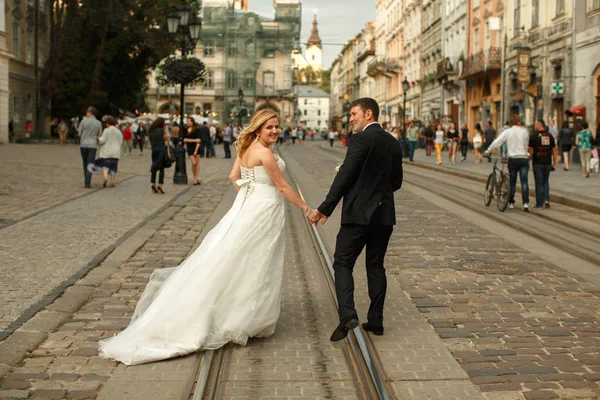 Nevěsta a ženich podívat přes rameno stojící na tramwa — Stock fotografie