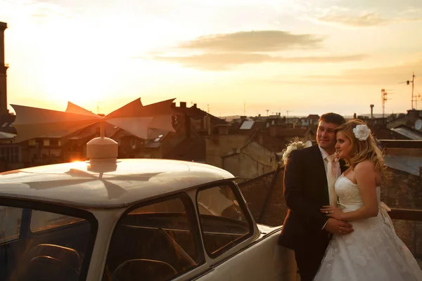 Braut und Bräutigam beobachten den Sonnenuntergang auf dem Dach stehend — Stockfoto