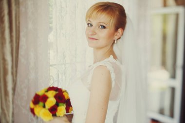 Gelin bir pencere arkasında bir buket ile gizemli ayakta görünüyor 