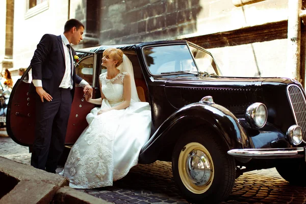 Bruidegom houdt een arm van een charmante bruid terwijl ze in een open zit — Stockfoto