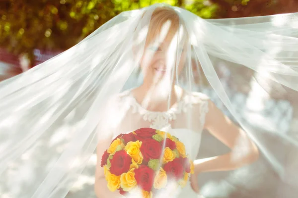 Wind covers bride's face with a veil while she smiles