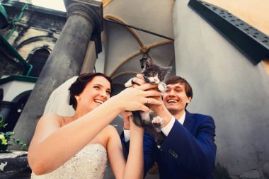 Gelin ve damat gülümseme komik bir kedi ile oynarken 