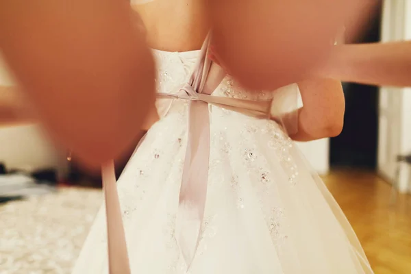 Las manos de la mujer ponen una cinta en un vestido de novia —  Fotos de Stock