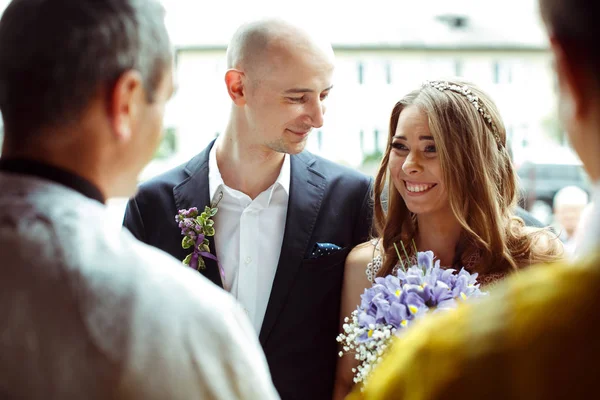 Sposo guarda una sposa sorridente in piedi davanti a un prete — Foto Stock