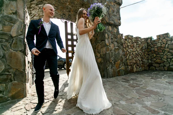 Novia y novio caminan bailando en el patio de piedra —  Fotos de Stock