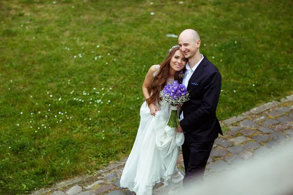 La cara de la novia brilla mientras el gromm la abraza de pie en el camino en —  Fotos de Stock