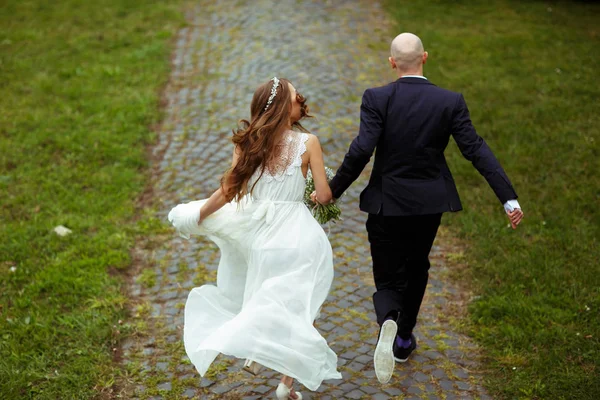 Blick von hinten auf das rennende Hochzeitspaar — Stockfoto