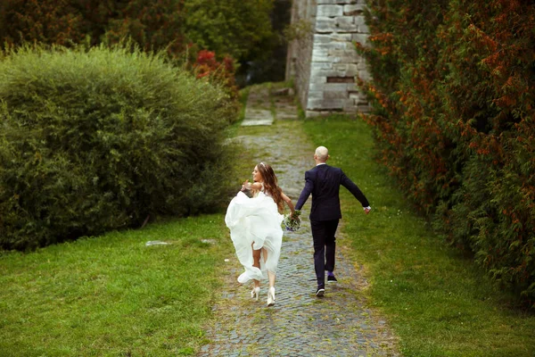 Vento soffia abito da sposa mentre lei corre con uno sposo — Foto Stock