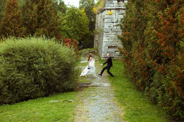 Groom acaricia uma noiva bonita andando em direção a ele no parque — Fotografia de Stock