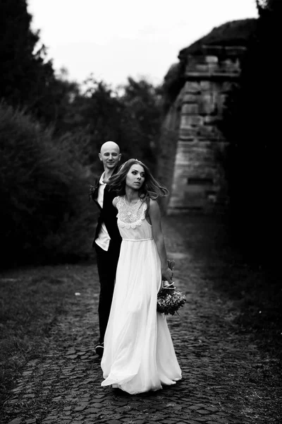 Noiva caminha ao longo do passo no parque segurando a mão do noivo — Fotografia de Stock