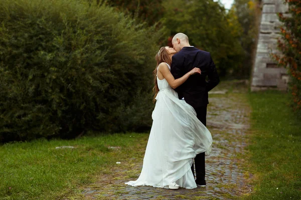 Bruid kussen een verloofde terwijl haar jurk betrekking heeft op zijn benen — Stockfoto