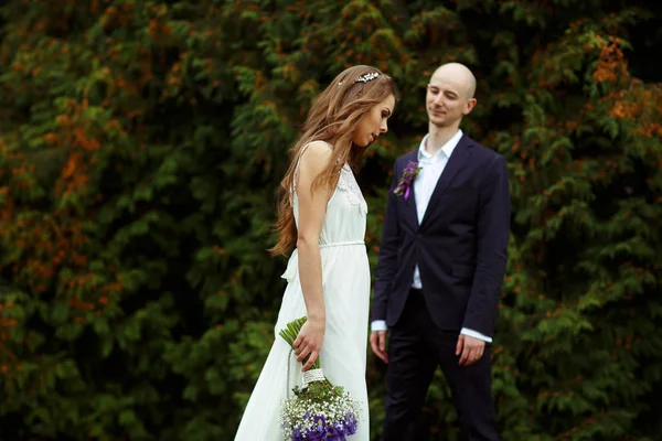 Noiva com um buquê de crocos violetas caminha atrás de um noivo — Fotografia de Stock