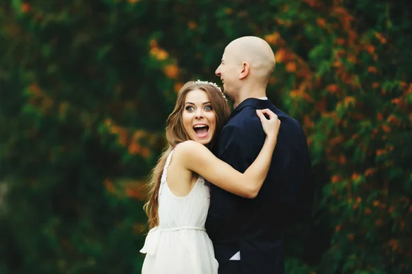 Noiva parece engraçado com os olhos abertos enquanto ela abraça um noivo — Fotografia de Stock