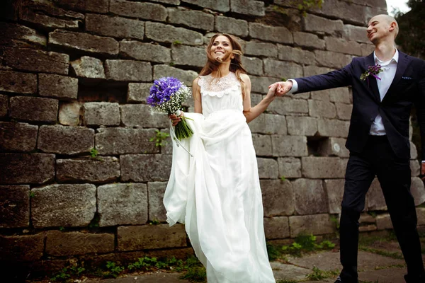 Nevěsta stojí rovně, drží za ruku ženicha a vítr se těší — Stock fotografie