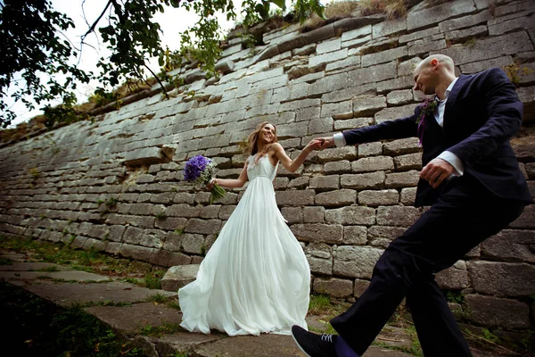 Ein Hochzeitspaar tanzt hinter einer Steinmauer — Stockfoto